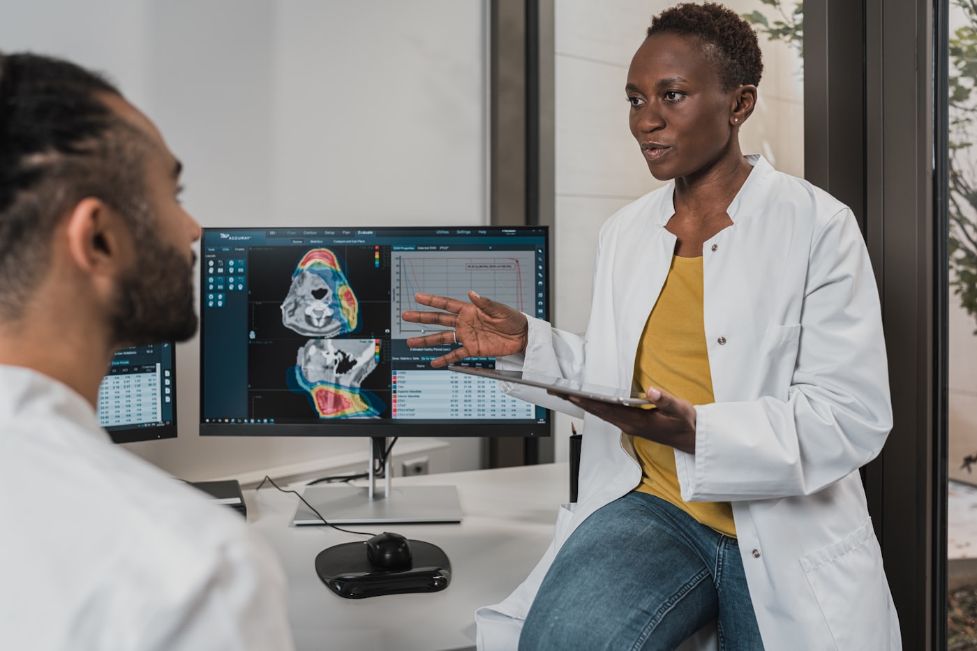 A clinician reviewing patient imaging on screen with a colleague